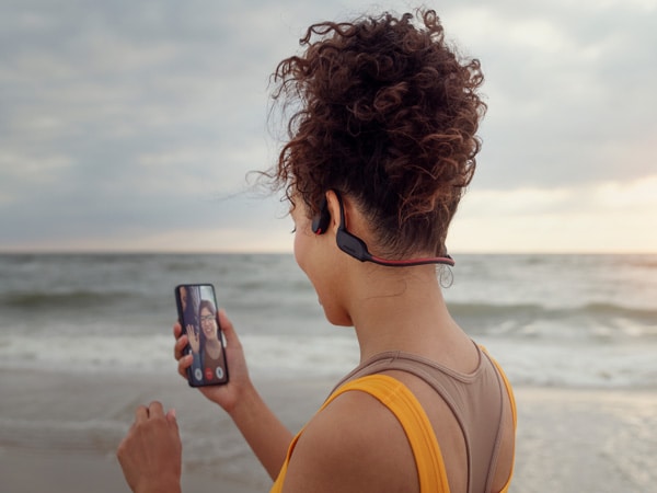 Žena uživa u funkciji kristalno jasnog glasa na Philips slušalicama koje koriste koštanu provodljivost
