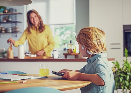 Dečak gleda video dok nosi Philips bežične slušalice za decu otvorenog dizajna