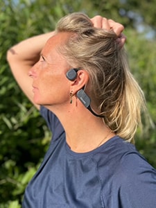 Žena nosi Philips Bluetooth slušalice sa tehnologijom koštane provodljivosti