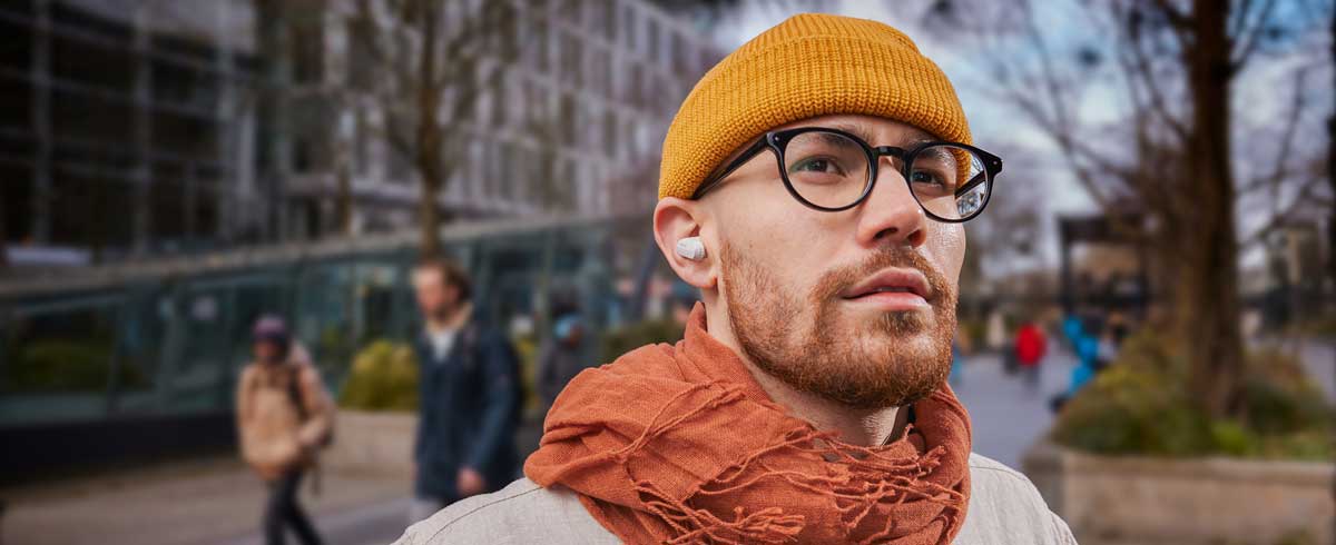 Fotografija čoveka iz krupnog plana koji nosi prave bežične slušalice