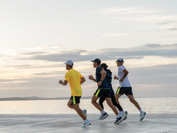 Četiri učesnika u trci trče zajedno na plaži.