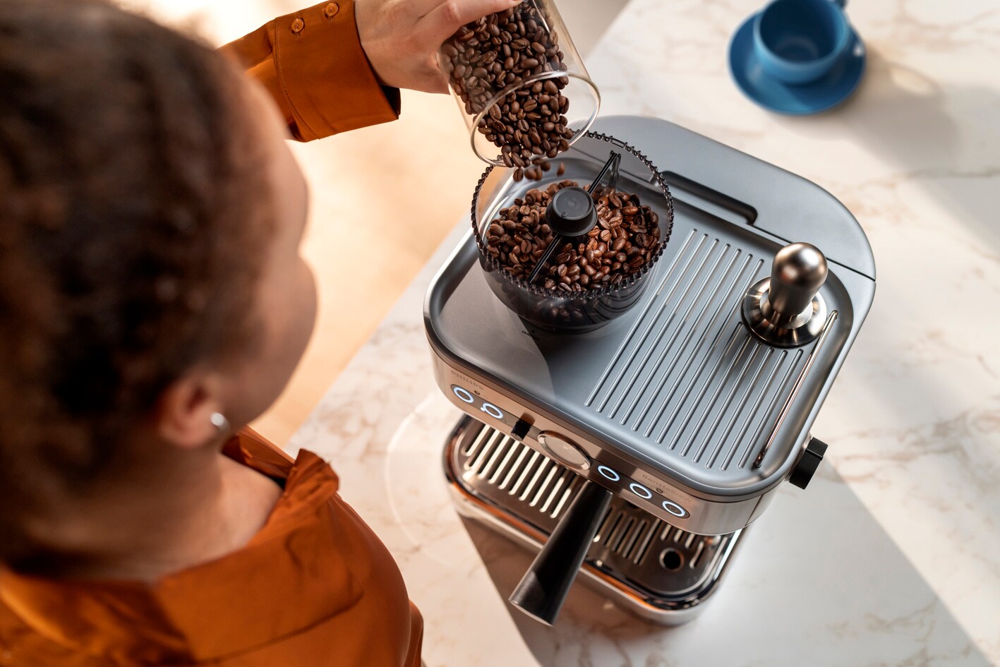 Devojka sipa kafu u zrnu u posudu na aparatu Philips Barista Brew